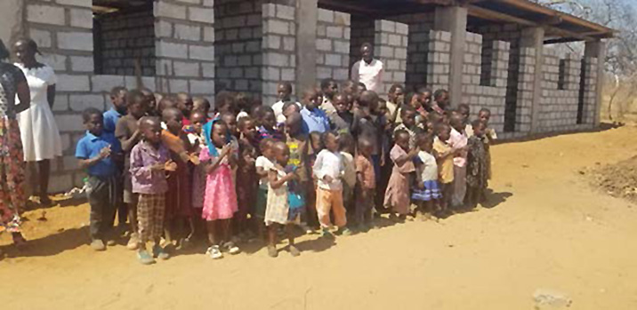 Image of children in front of cinderblock classrooms